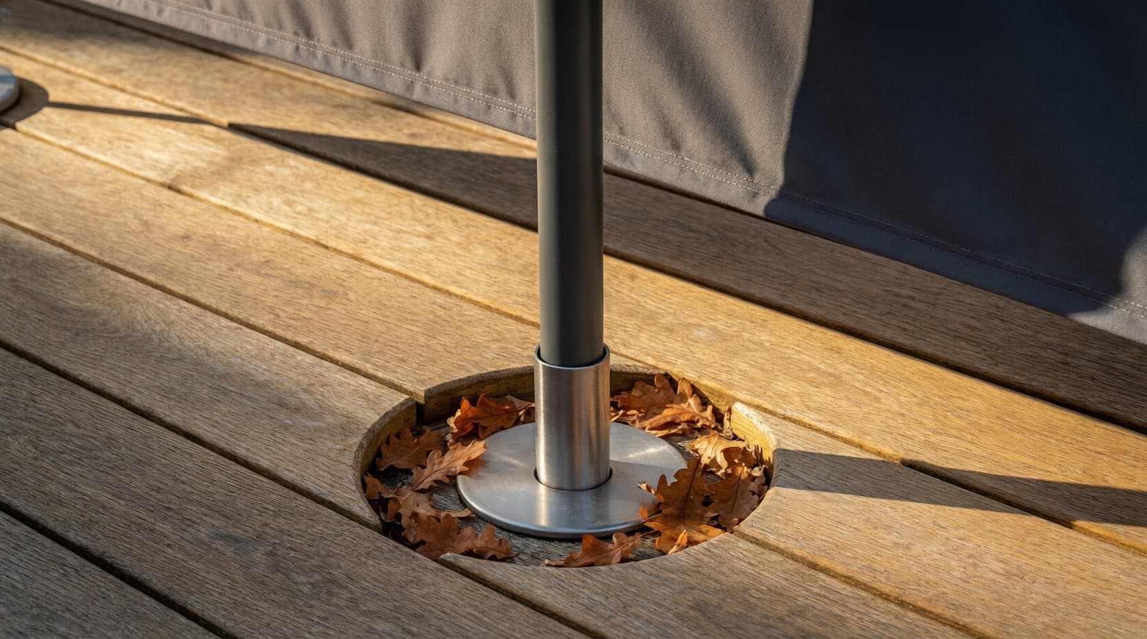 Mast eines Sonnenschirms in einer runden Bodenhülse im Holzdeck