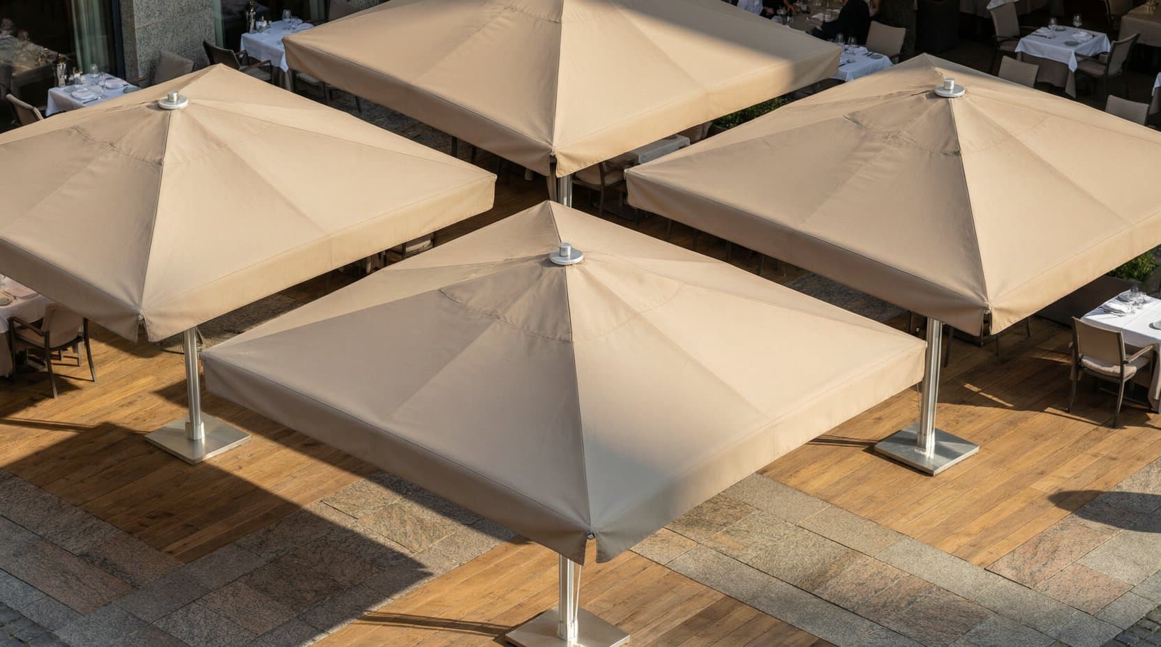 Hotelterrasse mit großen Sonnenschirmen, gedeckten Tischen und Gästen im Abendlicht